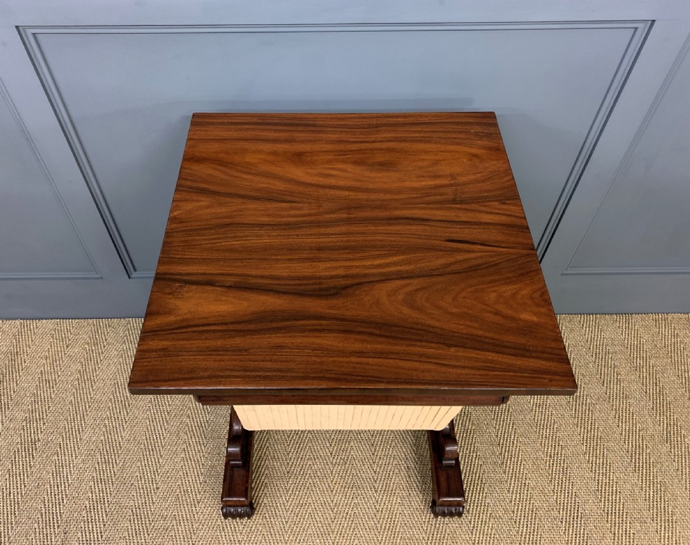 A William IV rosewood work table featuring a figured square top, pleated cream fabric basket, and carved scroll supports. View V