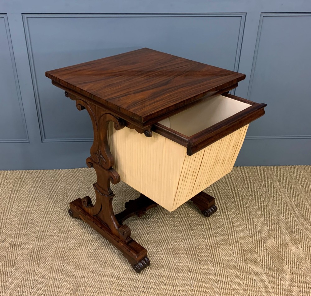 A William IV rosewood work table featuring a figured square top, pleated cream fabric basket, and carved scroll supports. View VII
