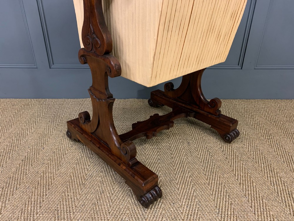 A William IV rosewood work table featuring a figured square top, pleated cream fabric basket, and carved scroll supports. View IX
