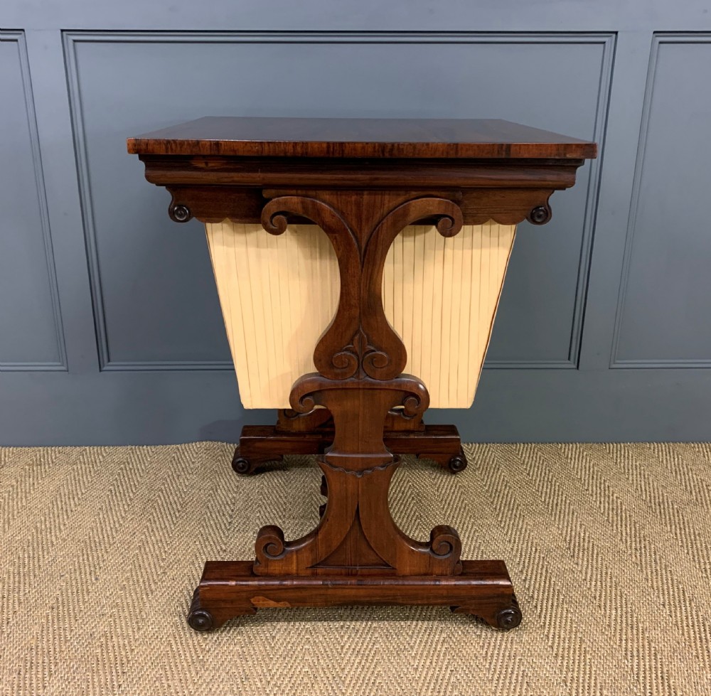 A William IV rosewood work table featuring a figured square top, pleated cream fabric basket, and carved scroll supports. View XI