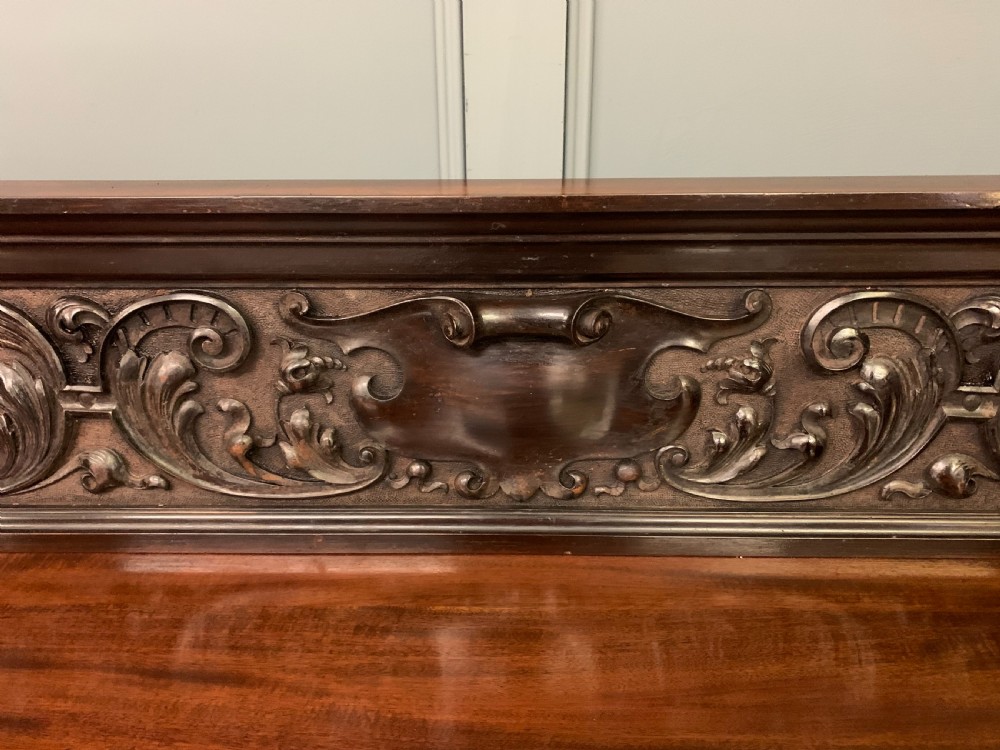 A Victorian mahogany buffet featuring a carved scroll backboard, two frieze drawers with brass handles, fluted support columns, and an open lower tier. View IX