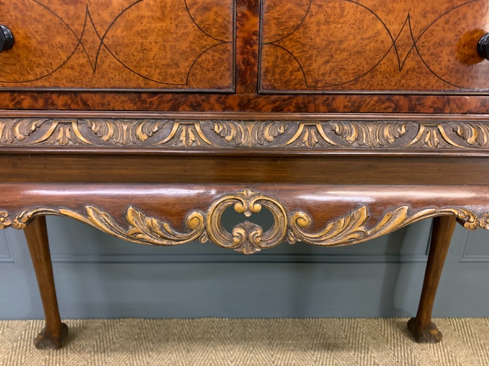 A burr walnut side table featuring two drawers with feather banding, carved egg-and-dart moulding, gilded accents, cabriole legs, and ball-and-claw feet. View V