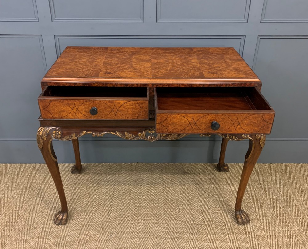 A burr walnut side table featuring two drawers with feather banding, carved egg-and-dart moulding, gilded accents, cabriole legs, and ball-and-claw feet. View VII