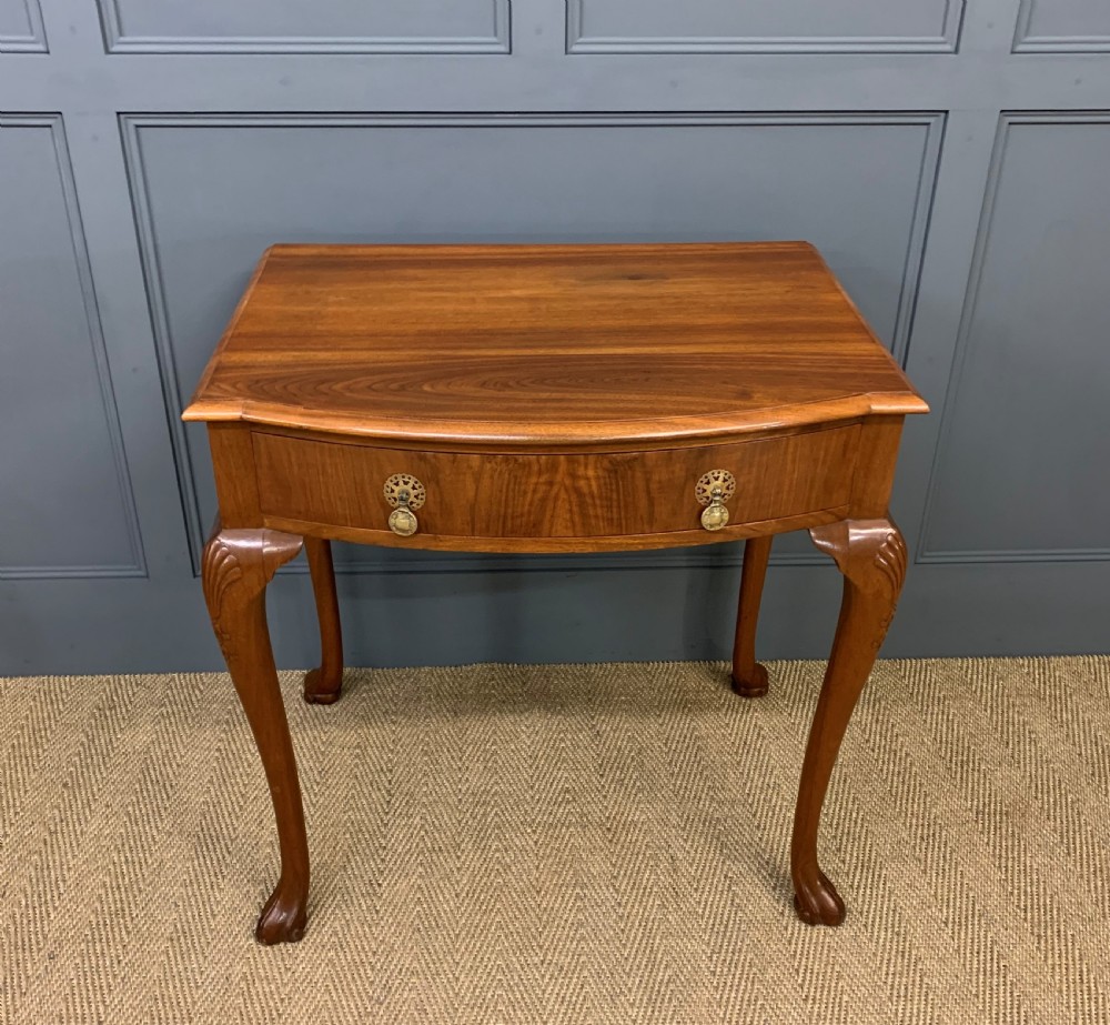 A warm brown burr walnut side table featuring a curved drawer front with brass handles and carved cabriole legs. View II