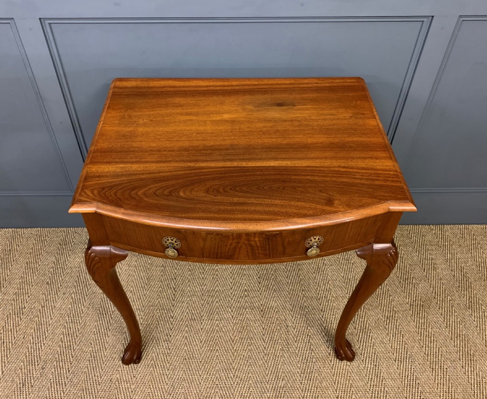 A warm brown burr walnut side table featuring a curved drawer front with brass handles and carved cabriole legs. View III