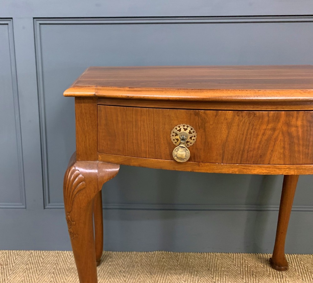 A warm brown burr walnut side table featuring a curved drawer front with brass handles and carved cabriole legs. View V