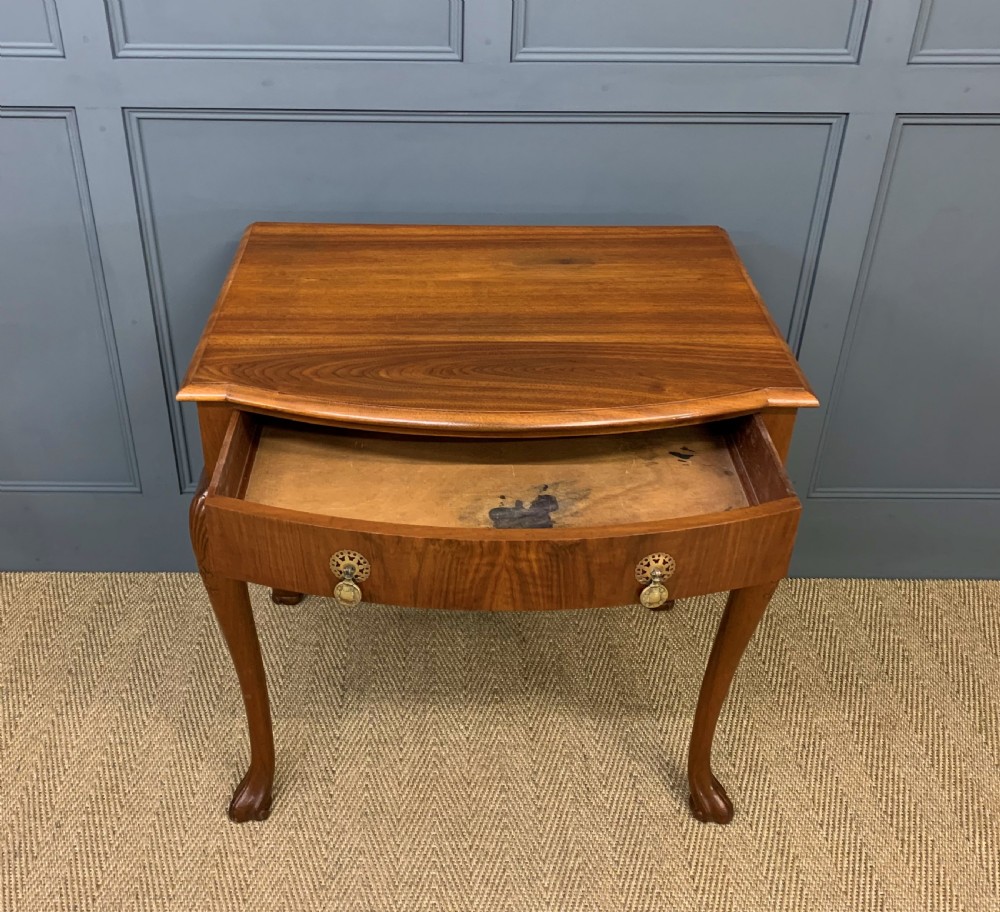 A warm brown burr walnut side table featuring a curved drawer front with brass handles and carved cabriole legs. View VI