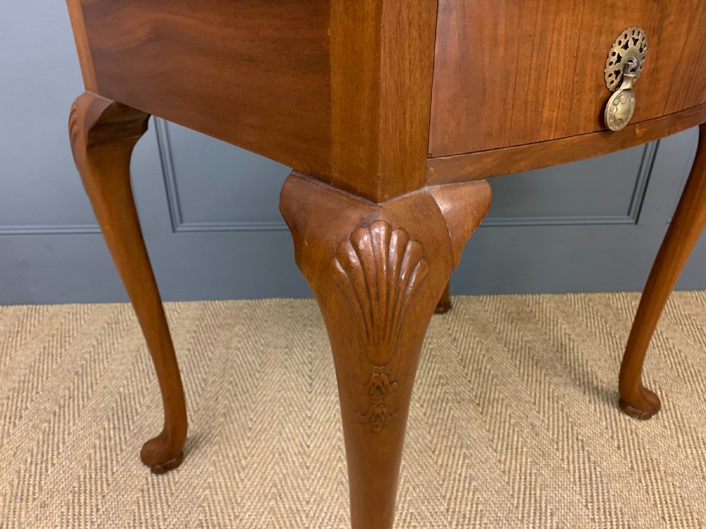 A warm brown burr walnut side table featuring a curved drawer front with brass handles and carved cabriole legs. View IX