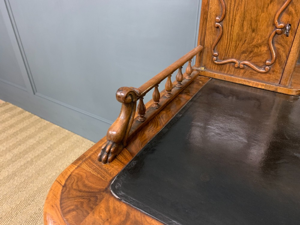 A 19th-century burr walnut bonheur du jour writing desk with a dark leather top, slender cabriole legs, and a gallery section featuring mirrors and small side cabinets. View V