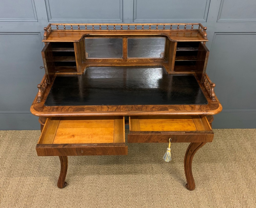 A 19th-century burr walnut bonheur du jour writing desk with a dark leather top, slender cabriole legs, and a gallery section featuring mirrors and small side cabinets. View X