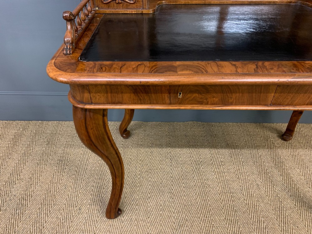 A 19th-century burr walnut bonheur du jour writing desk with a dark leather top, slender cabriole legs, and a gallery section featuring mirrors and small side cabinets. View XI