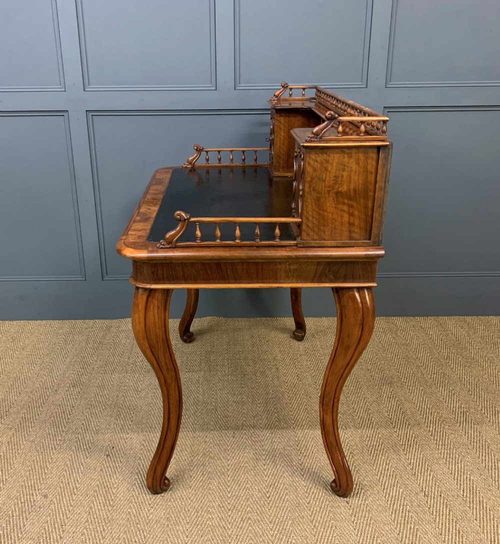 A 19th-century burr walnut bonheur du jour writing desk with a dark leather top, slender cabriole legs, and a gallery section featuring mirrors and small side cabinets. View XVII