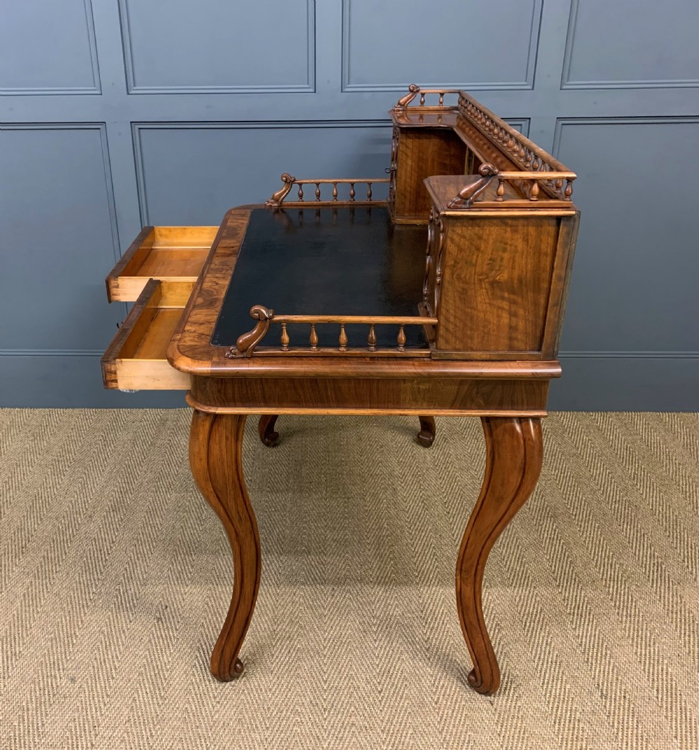 A 19th-century burr walnut bonheur du jour writing desk with a dark leather top, slender cabriole legs, and a gallery section featuring mirrors and small side cabinets. View XX