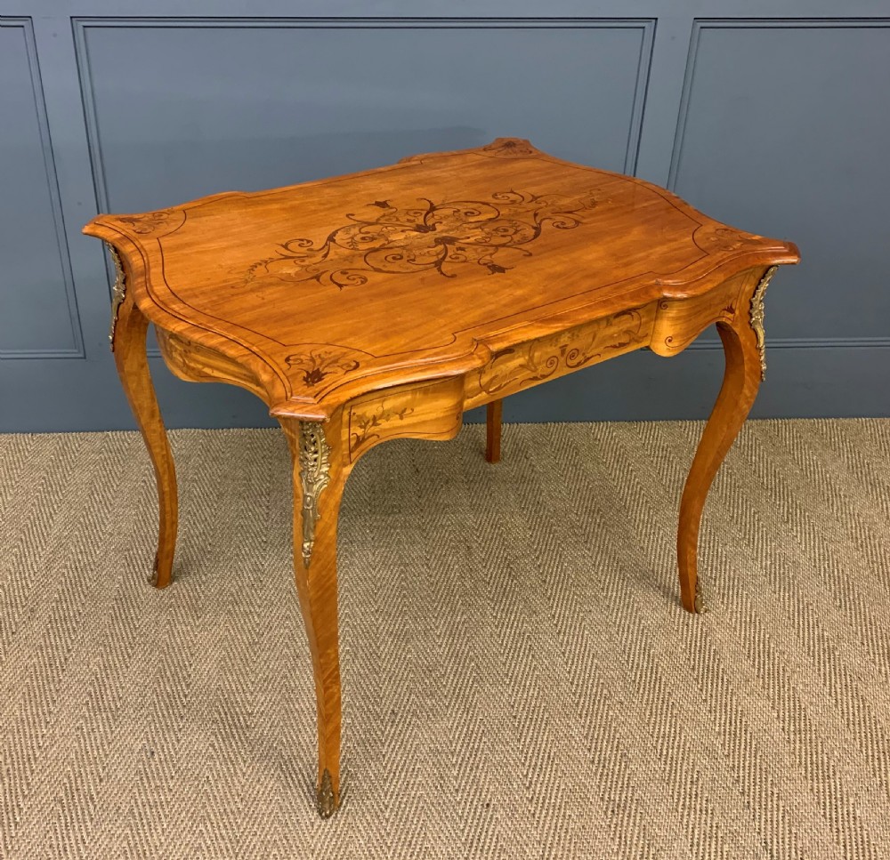 A 19th-century satinwood side table featuring floral marquetry inlay, serpentine edges, curved cabriole legs, and brass corner mounts.