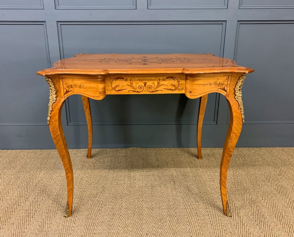 A 19th-century satinwood side table featuring floral marquetry inlay, serpentine edges, curved cabriole legs, and brass corner mounts. View VI