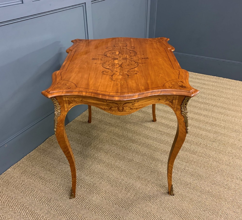 A 19th-century satinwood side table featuring floral marquetry inlay, serpentine edges, curved cabriole legs, and brass corner mounts. View XI