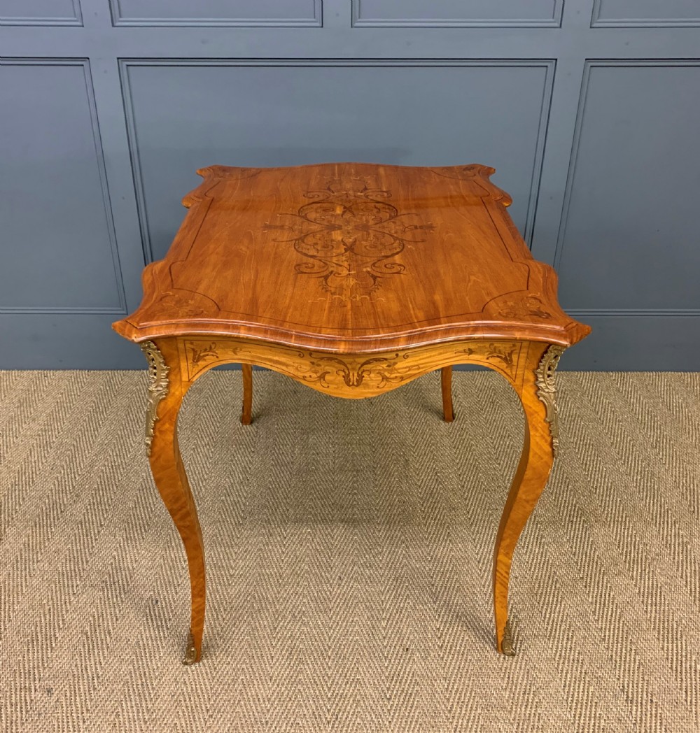 A 19th-century satinwood side table featuring floral marquetry inlay, serpentine edges, curved cabriole legs, and brass corner mounts. View XIII