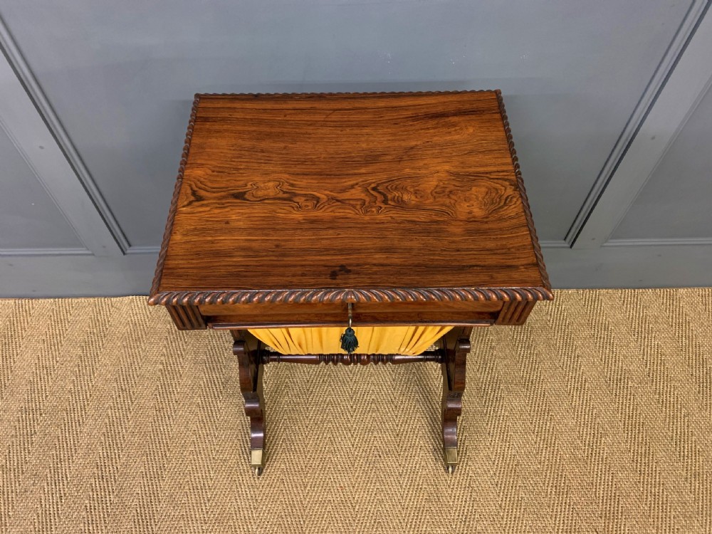 A Regency rosewood work table featuring a rectangular top with carved edging, a single drawer, a pleated yellow fabric storage well below, and trestle legs with brass castors. View III