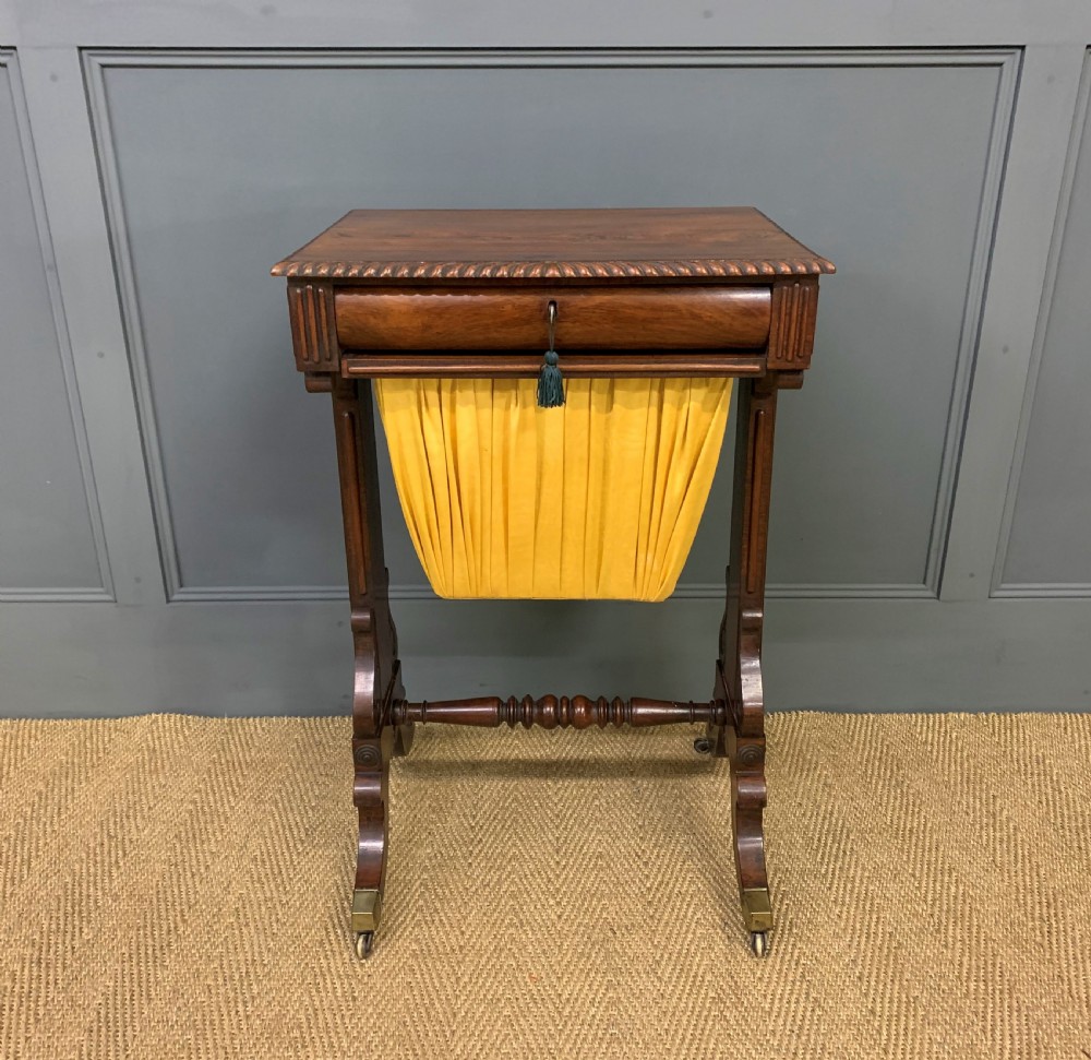 A Regency rosewood work table featuring a rectangular top with carved edging, a single drawer, a pleated yellow fabric storage well below, and trestle legs with brass castors. View IV