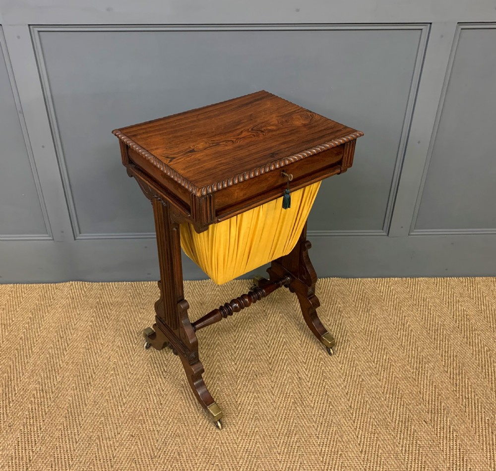 A Regency rosewood work table featuring a rectangular top with carved edging, a single drawer, a pleated yellow fabric storage well below, and trestle legs with brass castors. View VII