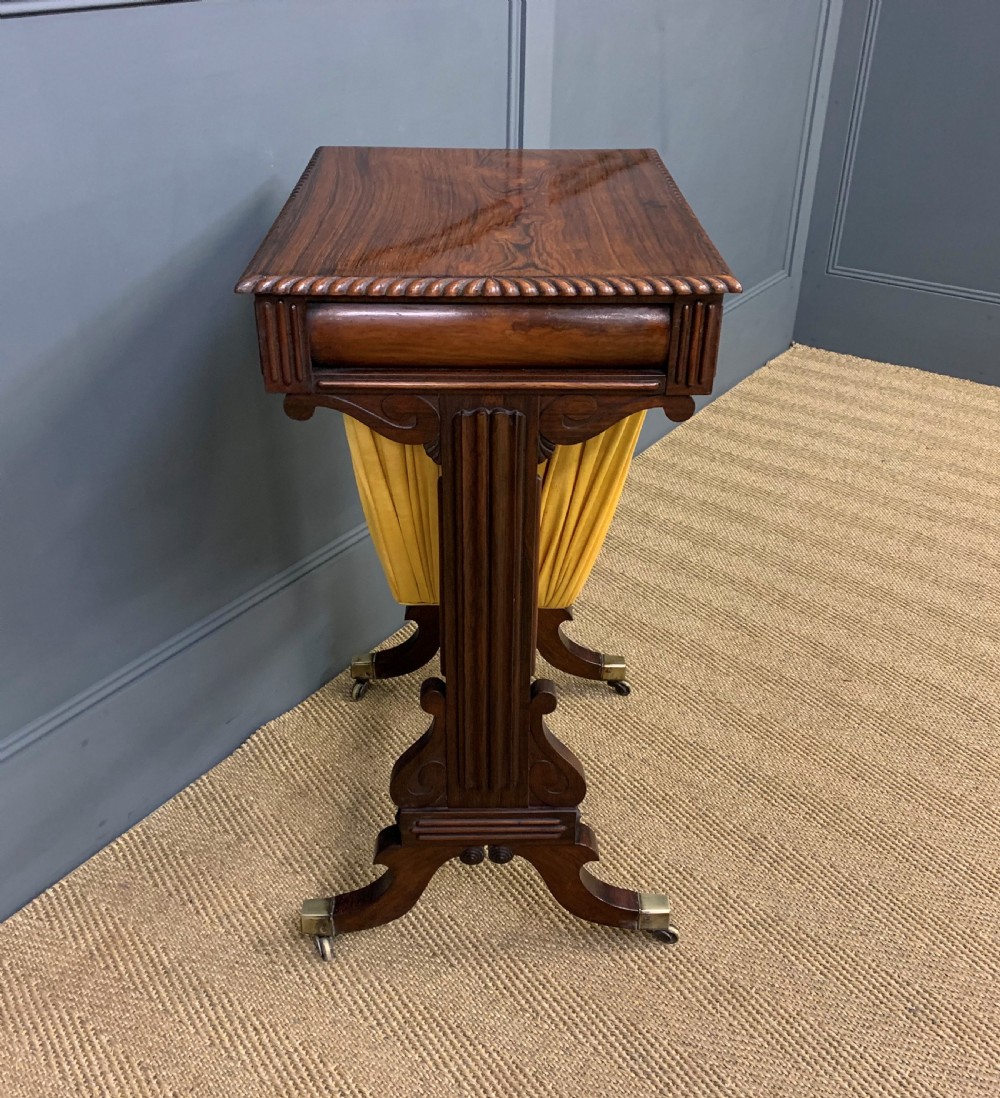 A Regency rosewood work table featuring a rectangular top with carved edging, a single drawer, a pleated yellow fabric storage well below, and trestle legs with brass castors. View XI