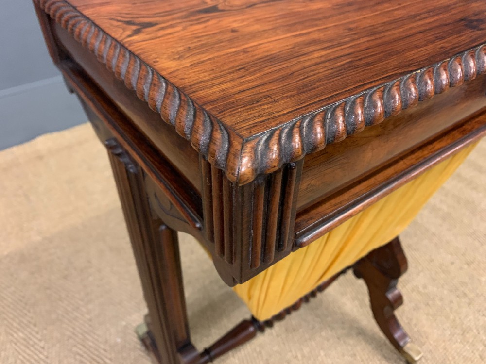 A Regency rosewood work table featuring a rectangular top with carved edging, a single drawer, a pleated yellow fabric storage well below, and trestle legs with brass castors. View XV