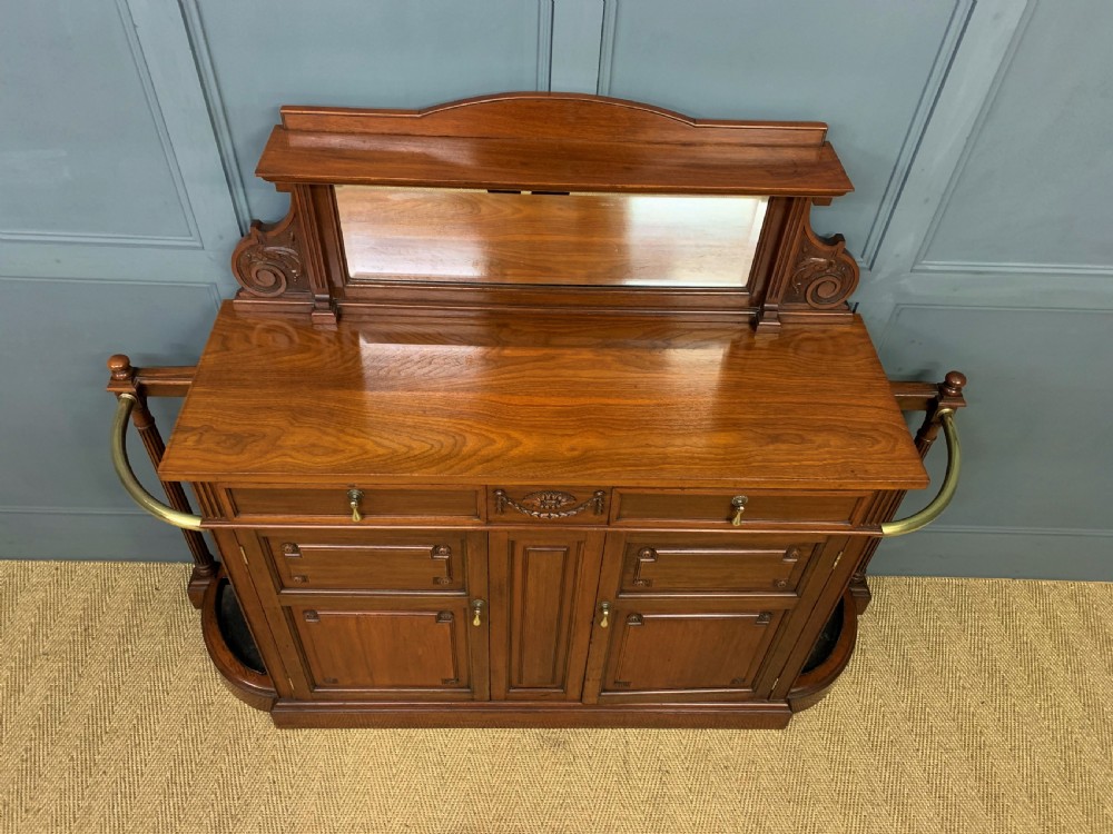 A Victorian walnut hall cupboard featuring a mirror back, two frieze drawers, panelled lower doors, and integrated side umbrella stands with brass rails. View II