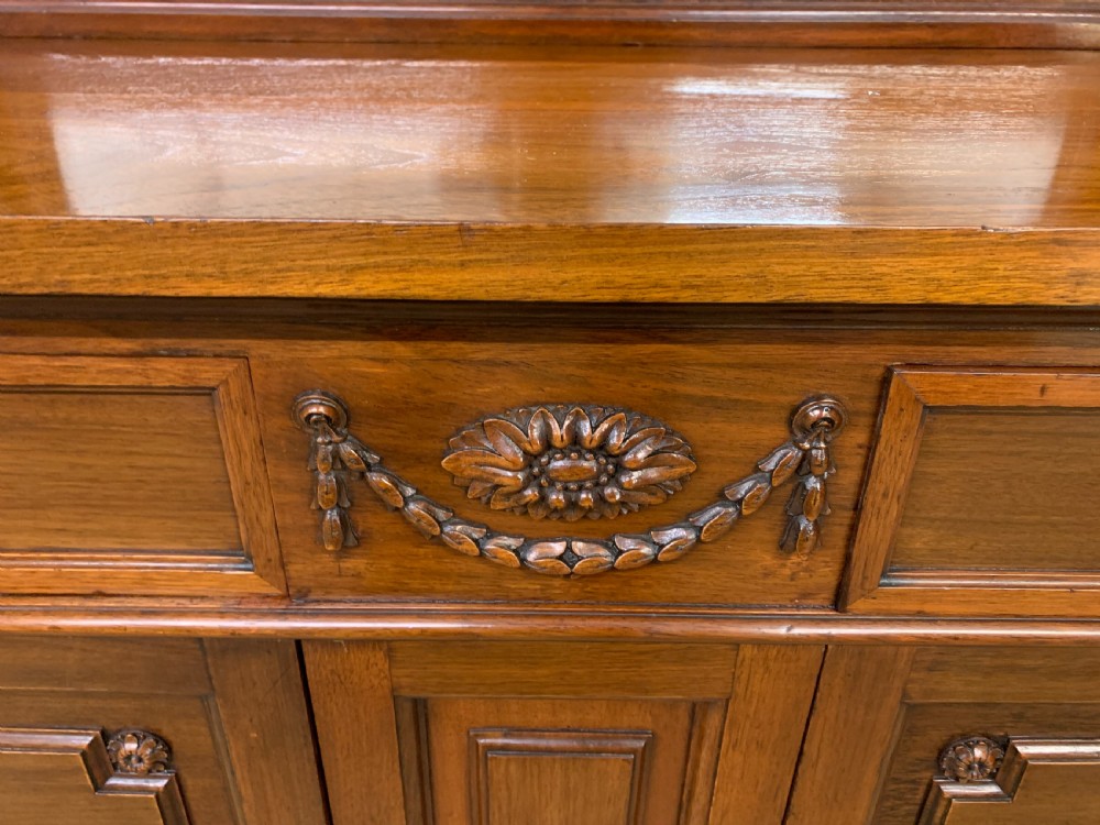 A Victorian walnut hall cupboard featuring a mirror back, two frieze drawers, panelled lower doors, and integrated side umbrella stands with brass rails. View V