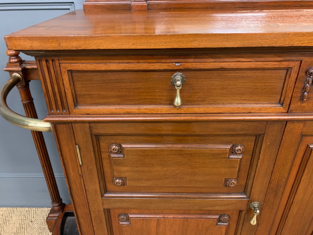 A Victorian walnut hall cupboard featuring a mirror back, two frieze drawers, panelled lower doors, and integrated side umbrella stands with brass rails. View VI