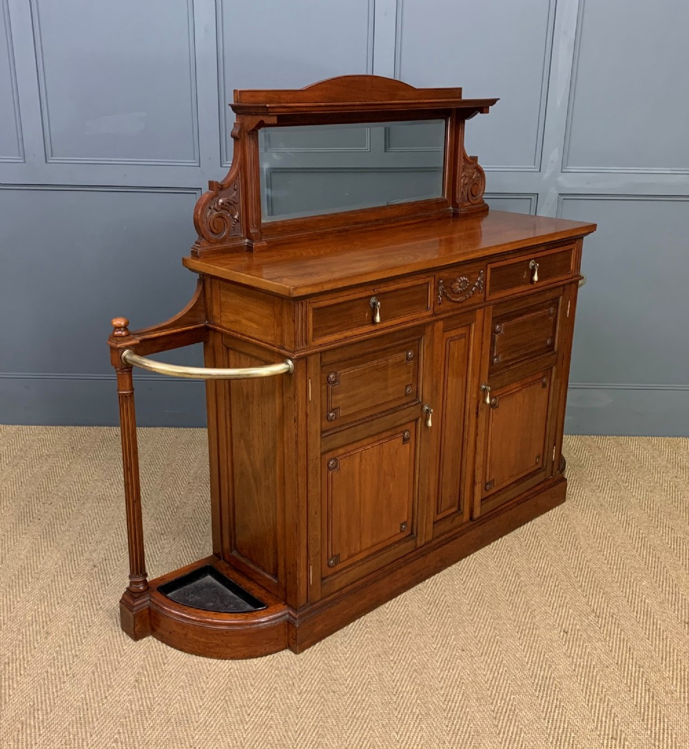 A Victorian walnut hall cupboard featuring a mirror back, two frieze drawers, panelled lower doors, and integrated side umbrella stands with brass rails. View IX