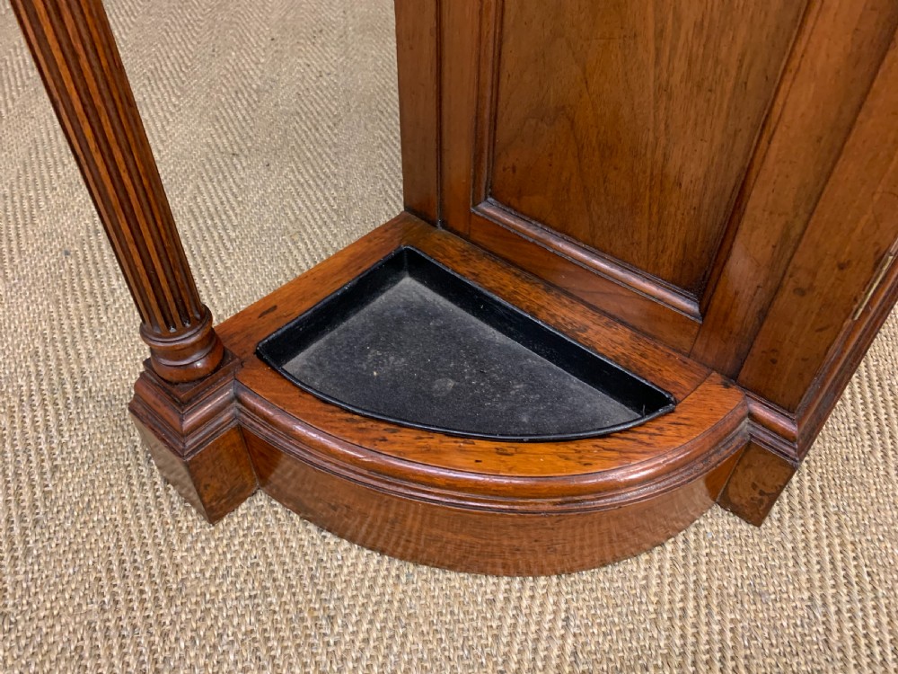 A Victorian walnut hall cupboard featuring a mirror back, two frieze drawers, panelled lower doors, and integrated side umbrella stands with brass rails. View XIII