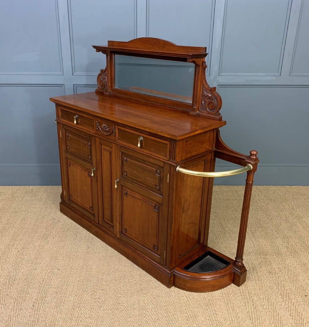 A Victorian walnut hall cupboard featuring a mirror back, two frieze drawers, panelled lower doors, and integrated side umbrella stands with brass rails. View XV