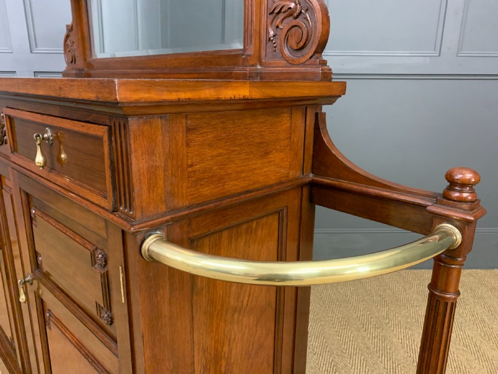 A Victorian walnut hall cupboard featuring a mirror back, two frieze drawers, panelled lower doors, and integrated side umbrella stands with brass rails. View XVII