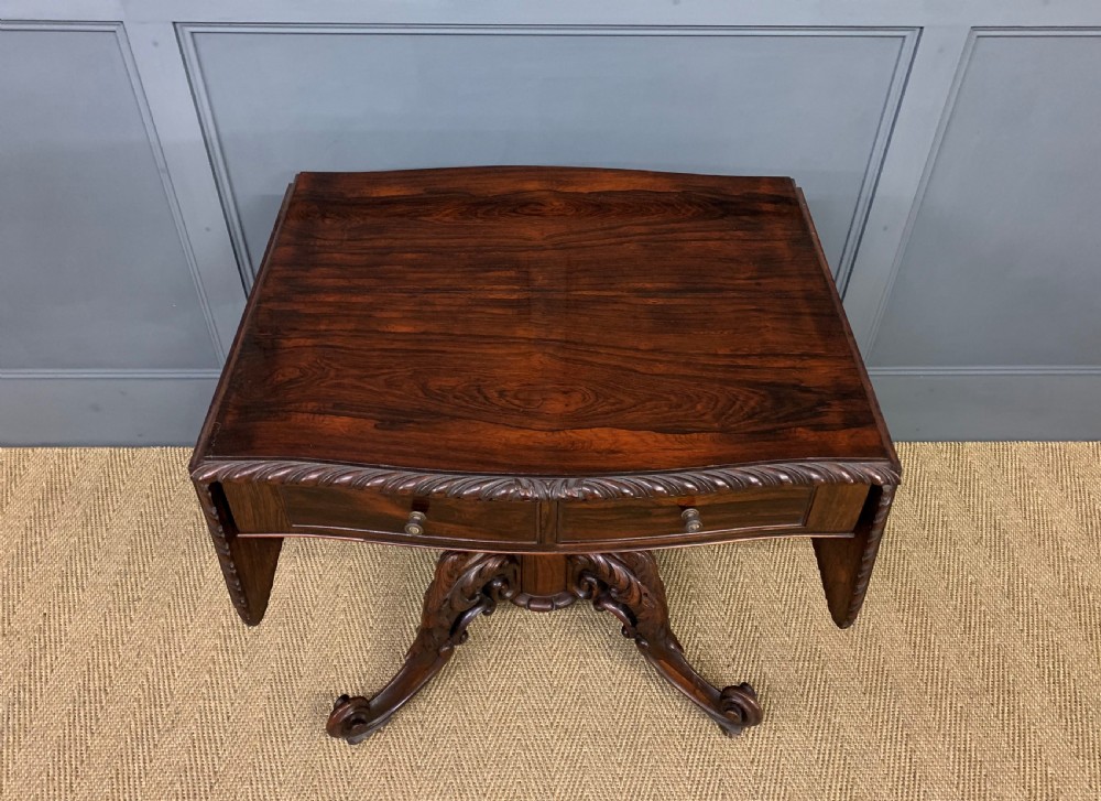 A 19th-century dark rosewood sofa table featuring drop leaves, two front frieze drawers, and an intricately carved central pedestal on scroll legs. View III