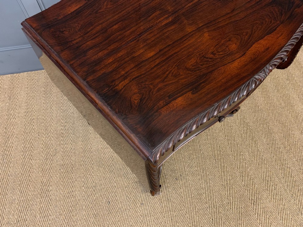 A 19th-century dark rosewood sofa table featuring drop leaves, two front frieze drawers, and an intricately carved central pedestal on scroll legs. View IX