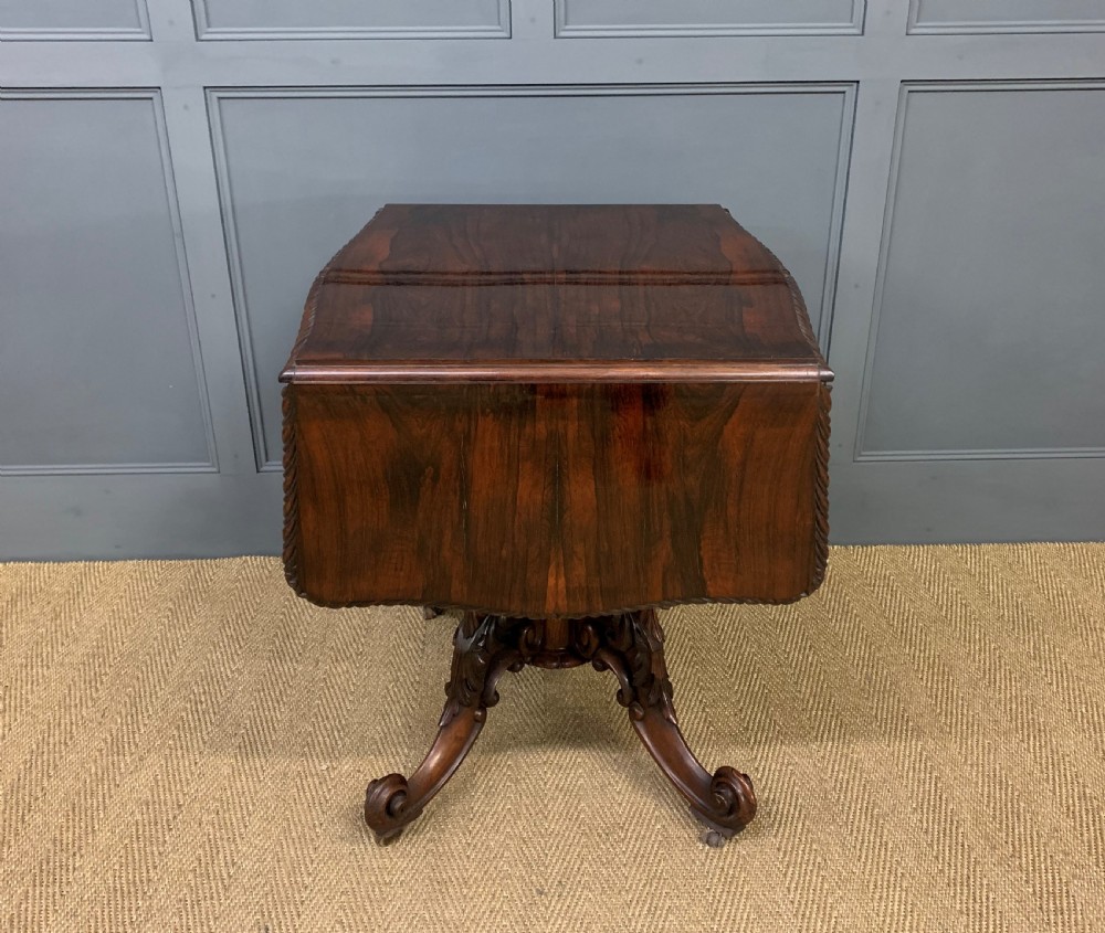 A 19th-century dark rosewood sofa table featuring drop leaves, two front frieze drawers, and an intricately carved central pedestal on scroll legs. View XIII