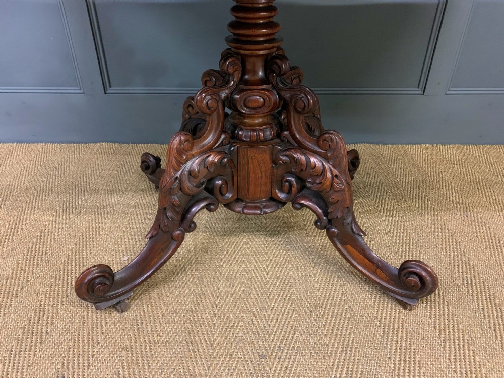 A 19th-century dark rosewood sofa table featuring drop leaves, two front frieze drawers, and an intricately carved central pedestal on scroll legs. View XVI