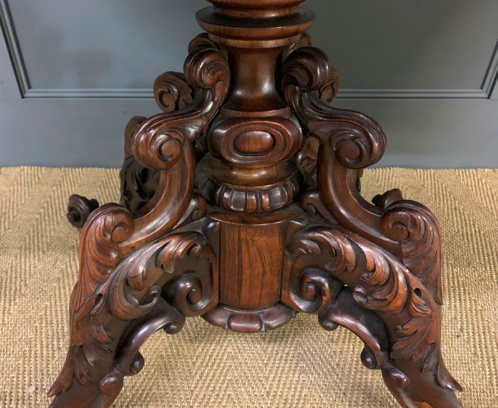 A 19th-century dark rosewood sofa table featuring drop leaves, two front frieze drawers, and an intricately carved central pedestal on scroll legs. View XVII
