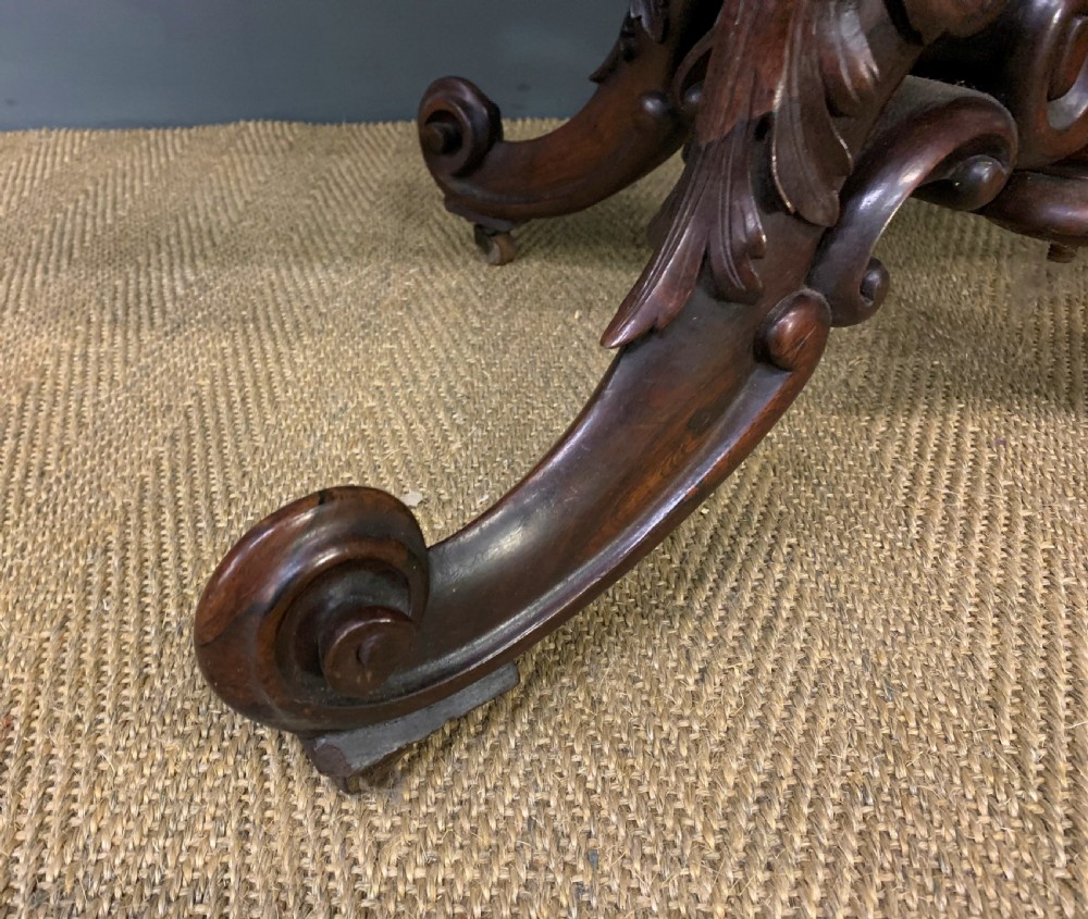 A 19th-century dark rosewood sofa table featuring drop leaves, two front frieze drawers, and an intricately carved central pedestal on scroll legs. View XVIII