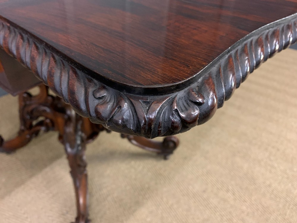 A 19th-century dark rosewood sofa table featuring drop leaves, two front frieze drawers, and an intricately carved central pedestal on scroll legs. View XXIII