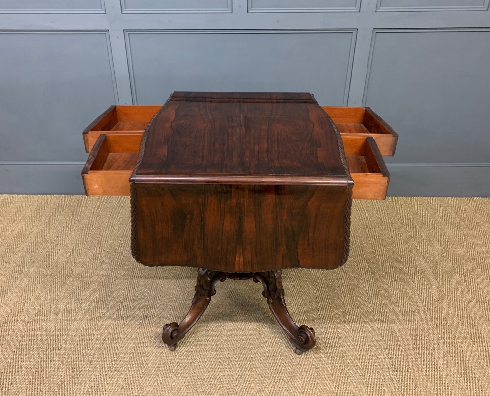 A 19th-century dark rosewood sofa table featuring drop leaves, two front frieze drawers, and an intricately carved central pedestal on scroll legs. View XXIV