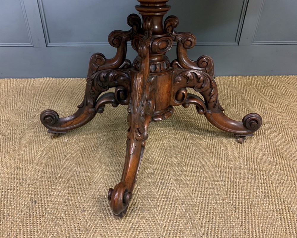 A 19th-century dark rosewood sofa table featuring drop leaves, two front frieze drawers, and an intricately carved central pedestal on scroll legs. View XXVI