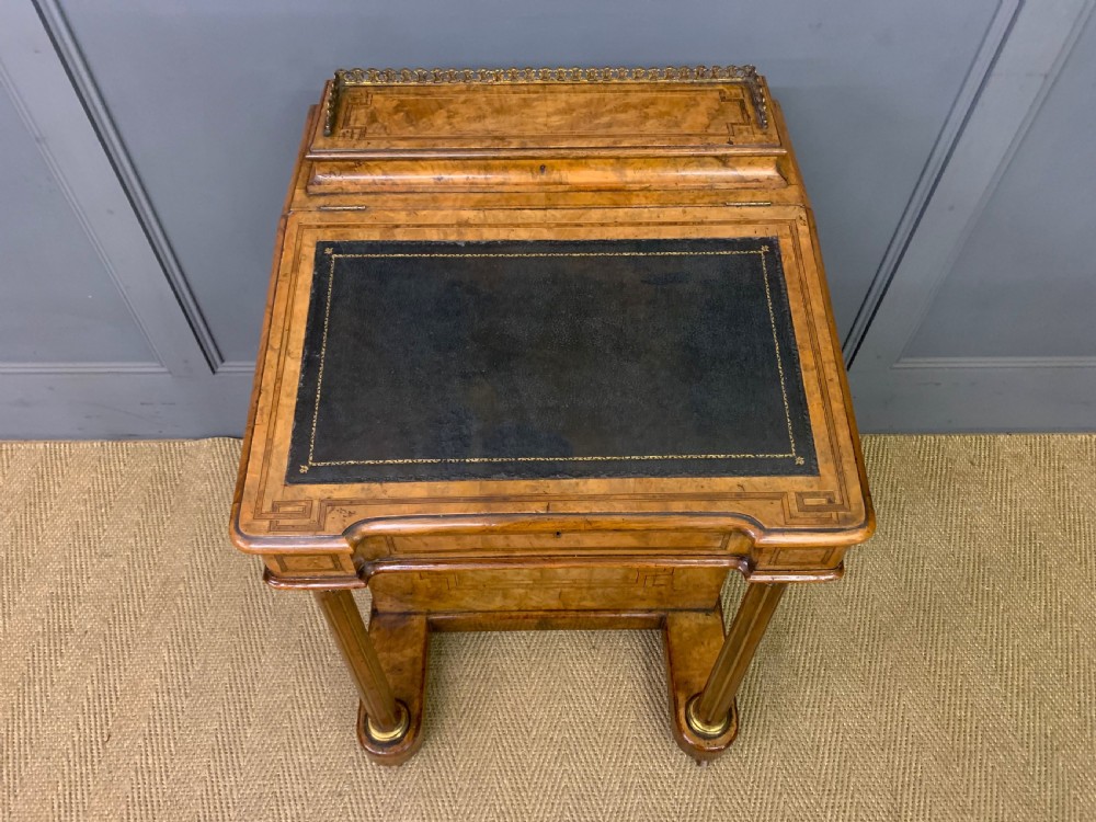 A Victorian burr walnut davenport desk featuring a sloped dark leather inset writing surface, brass gallery rail, side drawers, and fluted column supports. View III