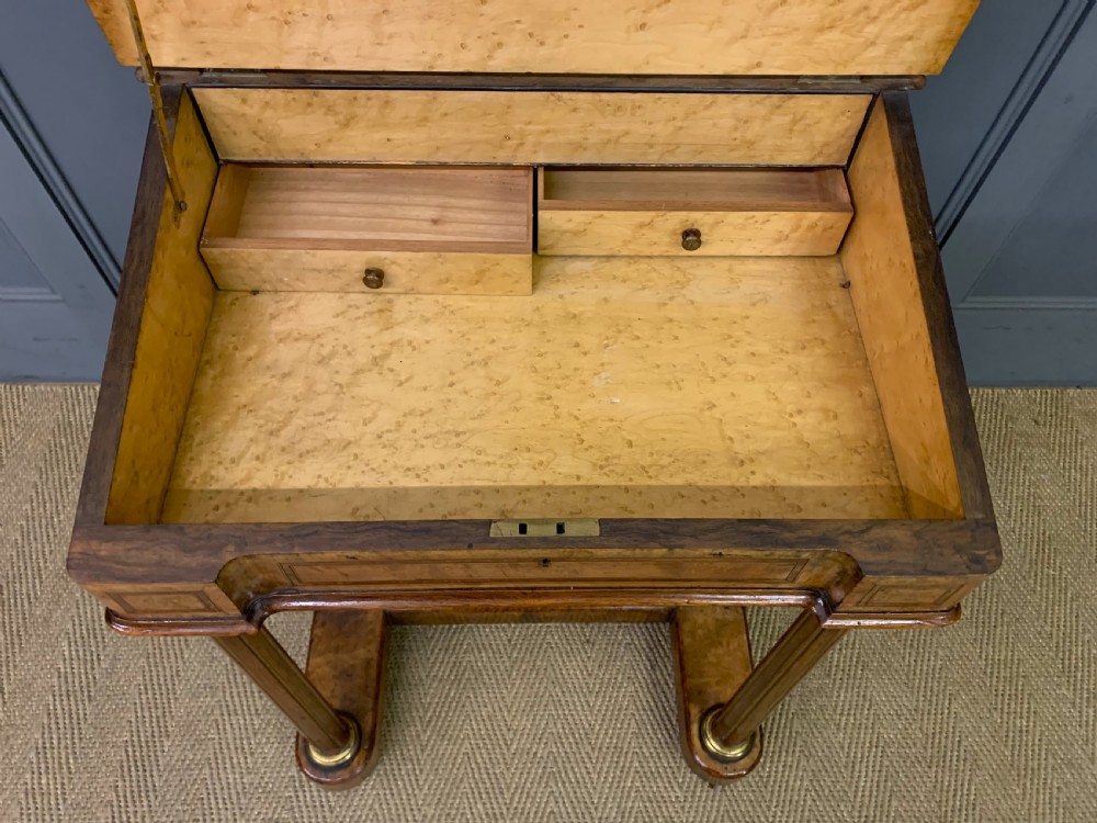 A Victorian burr walnut davenport desk featuring a sloped dark leather inset writing surface, brass gallery rail, side drawers, and fluted column supports. View XI