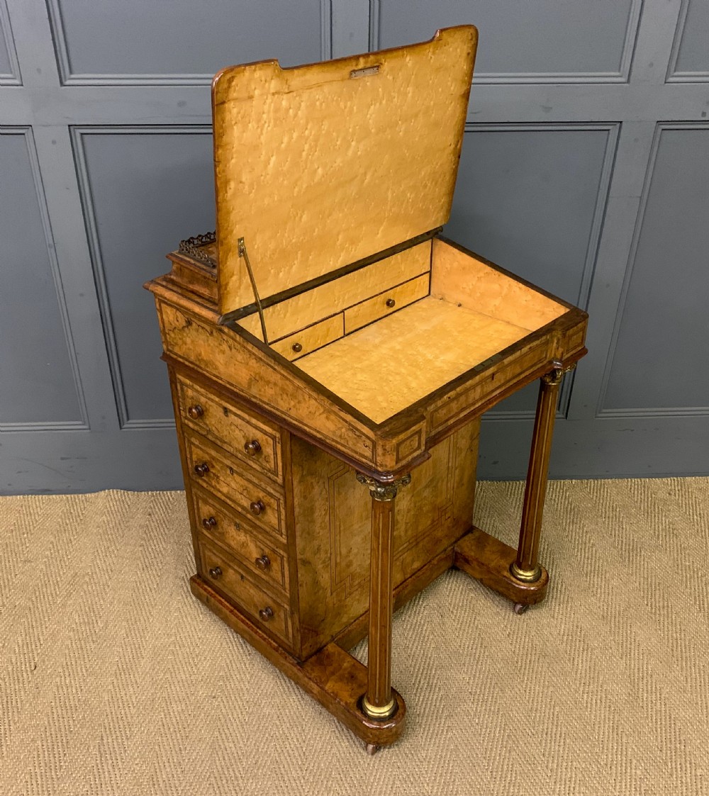 A Victorian burr walnut davenport desk featuring a sloped dark leather inset writing surface, brass gallery rail, side drawers, and fluted column supports. View XII
