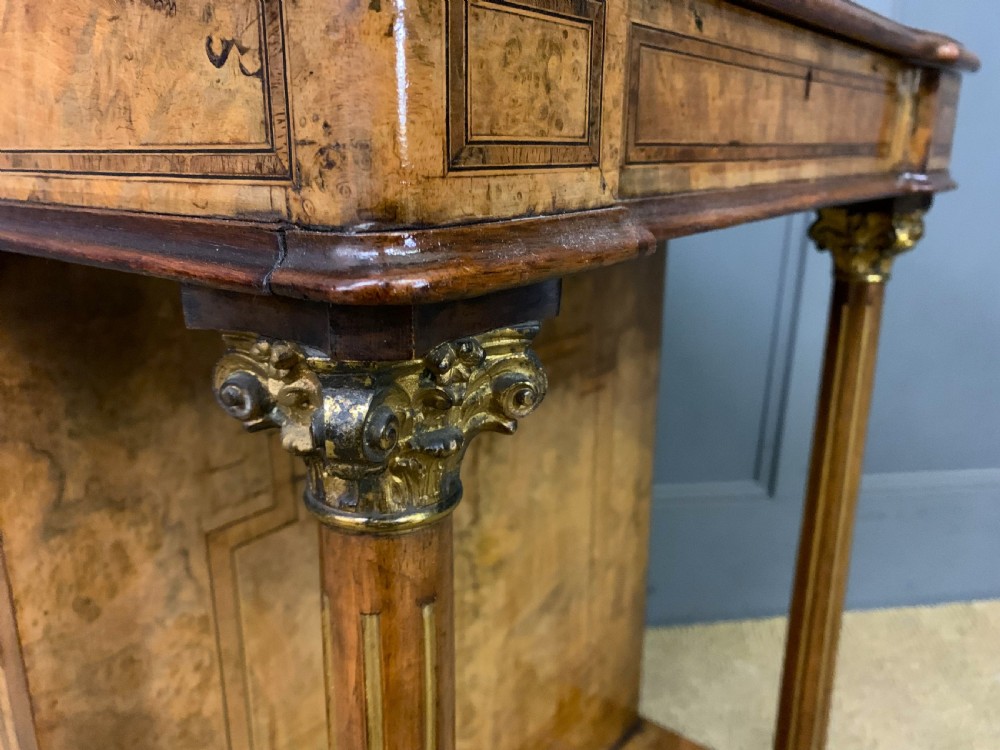 A Victorian burr walnut davenport desk featuring a sloped dark leather inset writing surface, brass gallery rail, side drawers, and fluted column supports. View XIV