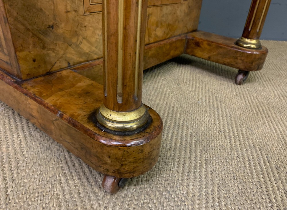 A Victorian burr walnut davenport desk featuring a sloped dark leather inset writing surface, brass gallery rail, side drawers, and fluted column supports. View XV