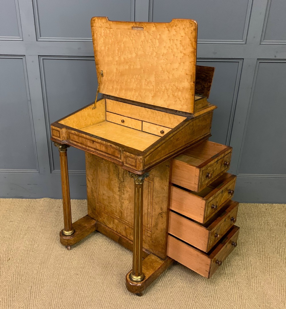 A Victorian burr walnut davenport desk featuring a sloped dark leather inset writing surface, brass gallery rail, side drawers, and fluted column supports. View XVIII