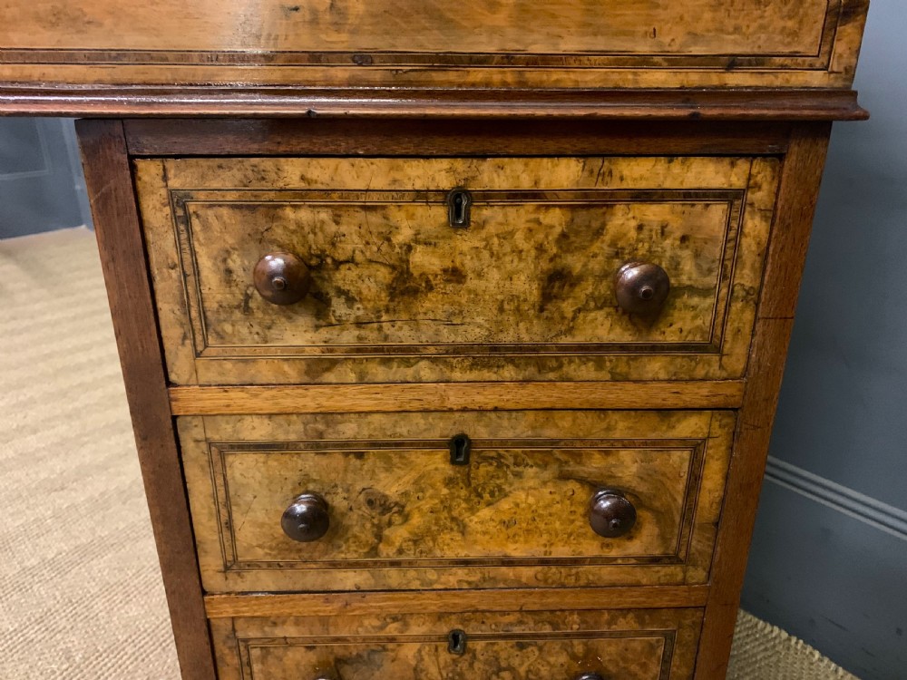 A Victorian burr walnut davenport desk featuring a sloped dark leather inset writing surface, brass gallery rail, side drawers, and fluted column supports. View XIX