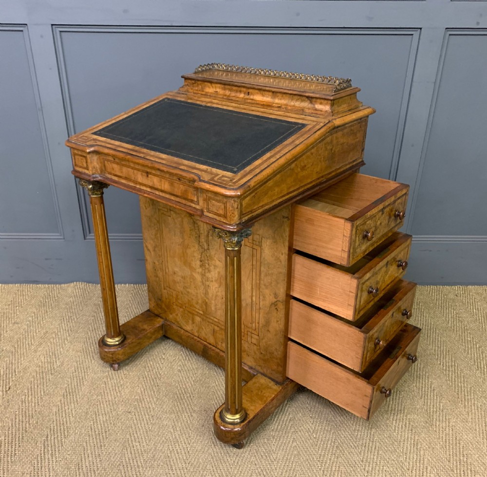 A Victorian burr walnut davenport desk featuring a sloped dark leather inset writing surface, brass gallery rail, side drawers, and fluted column supports. View XXI